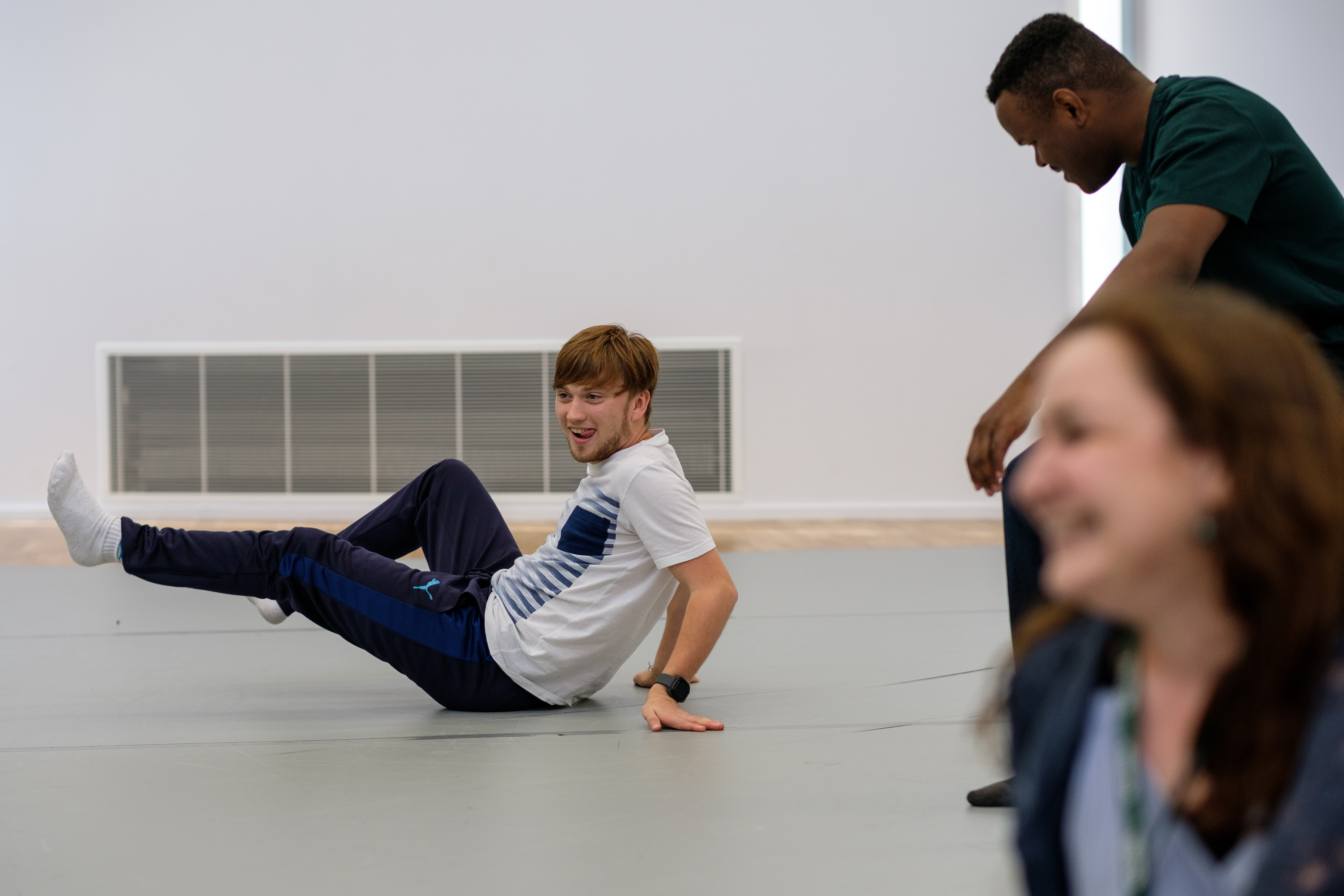 Three people take part in a workshop in a drama studio