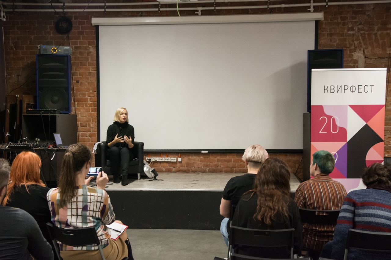 Seated figure speaking in front of an audience